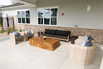 A patio with a black couch and a wooden coffee table.
